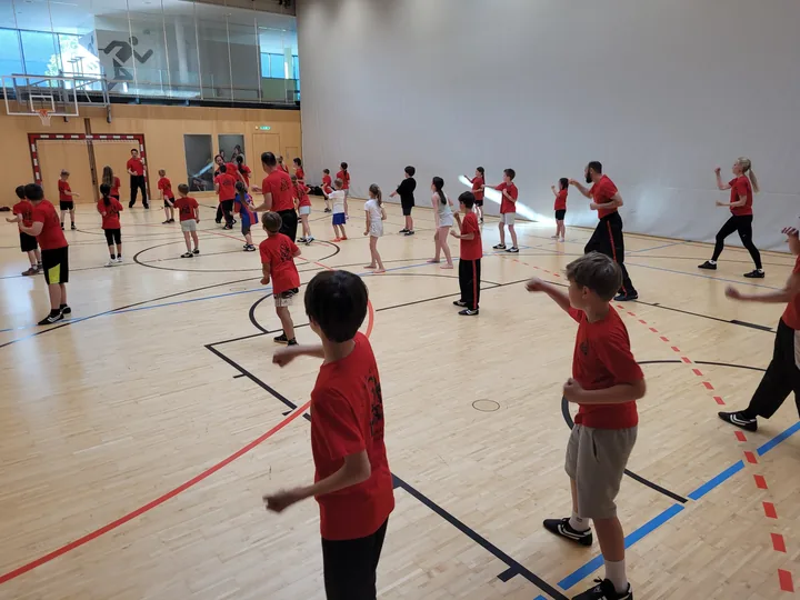 Kinder und Trainer üben Fausttechniken im gemeinsamen Training