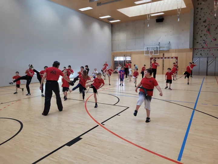 Kinder trainieren gleichzeitig Tritte in der großen Turnhalle