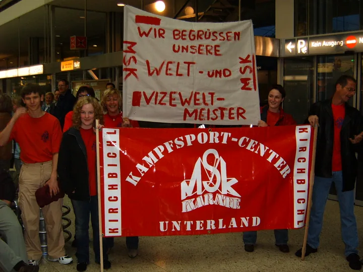 Vereinsmitglieder begrüßen erfolgreiche Weltmeister mit einem Banner