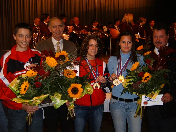 Junge Sportlerinnen und Sportler mit Medaillen und Blumen bei einer Ehrung